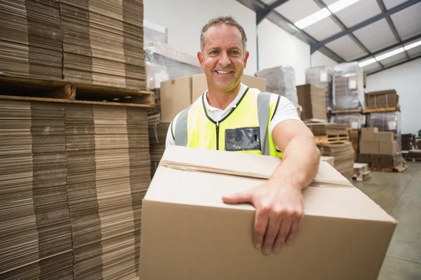 Worker carrying box in warehouse — Stock Photo, Image