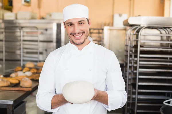 Улыбающийся пекарь держит сырое тесто — стоковое фото
