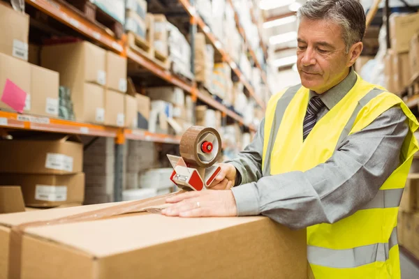 Magazijn werknemer afdichten van kartonnen dozen voor verzending — Stockfoto