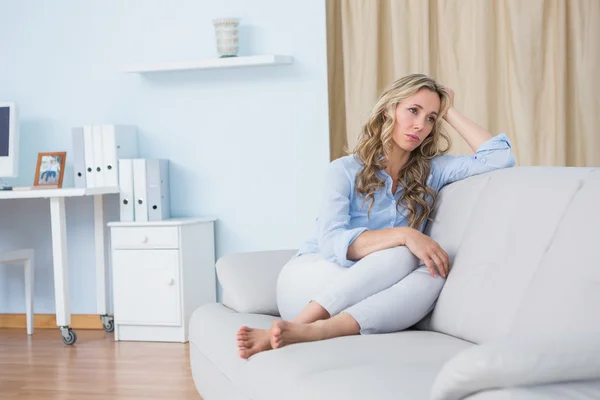 Frau sitzt auf Couch und denkt nach — Stockfoto