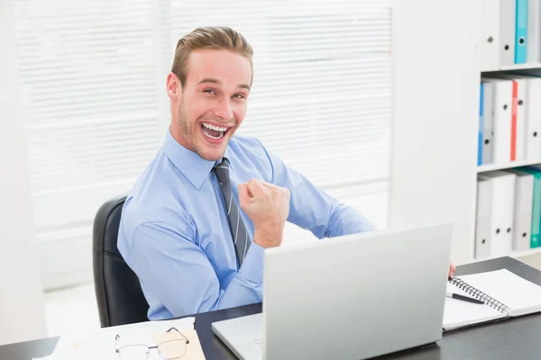 Excited businessman sitting at desk cheering — Stock Photo, Image