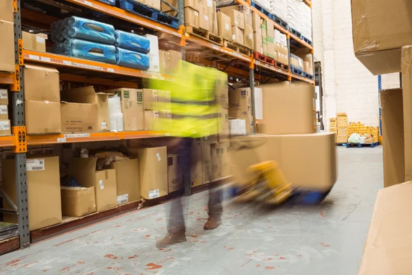 Worker pulling trolley with boxes in a blur — Stock Photo, Image