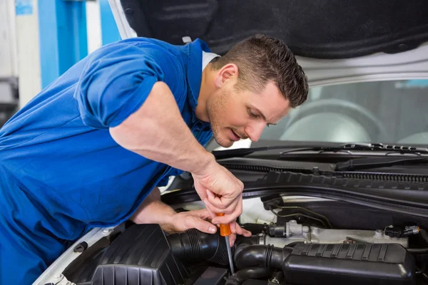 Mechanic using screwdriver on engine — Stock Photo, Image