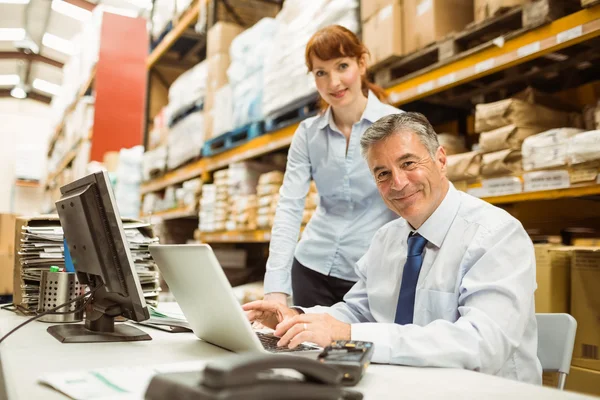 Warehouse management prata och titta på laptop — Stockfoto