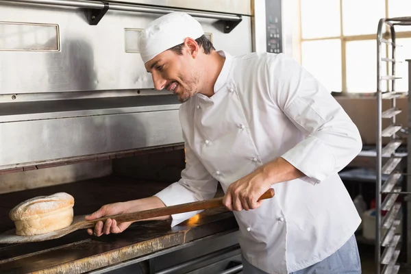 Happy baker taking out fresh loaf — Stock Photo, Image