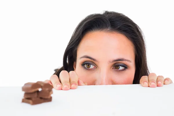 Mooie brunette gluren op chocolade — Stockfoto
