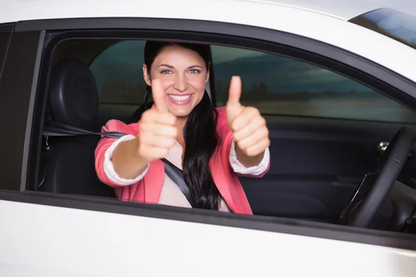Leende kvinna ger tummen upp i hennes bil — Stockfoto