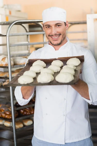 Smiling baker holding tray of raw dough — Stock Photo, Image