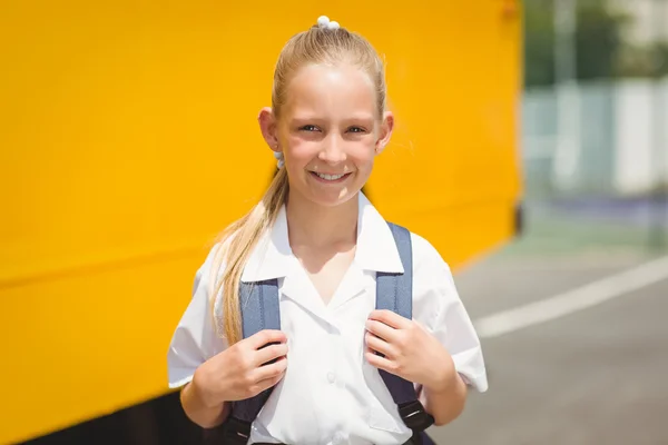 Aluno bonito sorrindo para a câmera pelo ônibus escolar — Fotografia de Stock