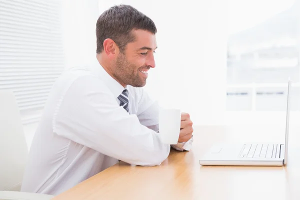 Affärsman anläggning mugg vid skrivbord — Stockfoto