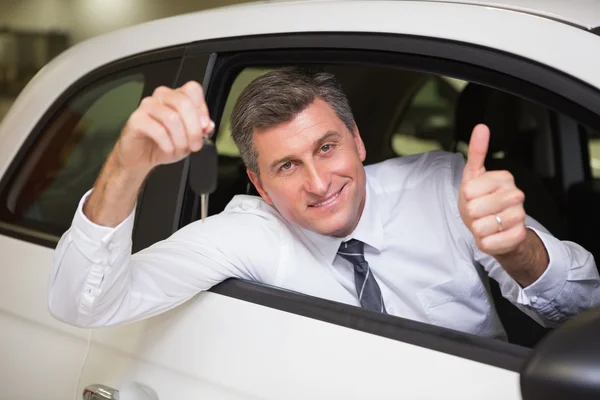 Homme souriant tenant une clé de voiture donnant pouces vers le haut — Photo