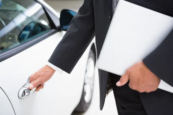 Man holding a car door handles while holding clipboard — Stock Photo, Image