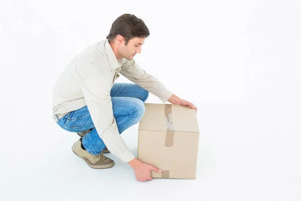 Delivery man picking cardboard box — Stock Photo, Image
