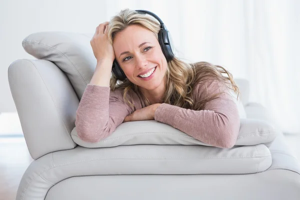 Blonde liggend op couch luisteren muziek — Stockfoto