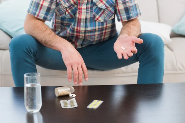 Man sitter på soffan håller piller — Stockfoto