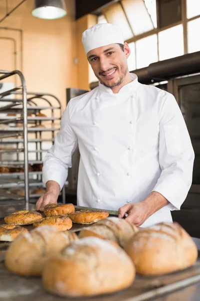 Happy baker taking out fresh bagels — Stock Photo, Image