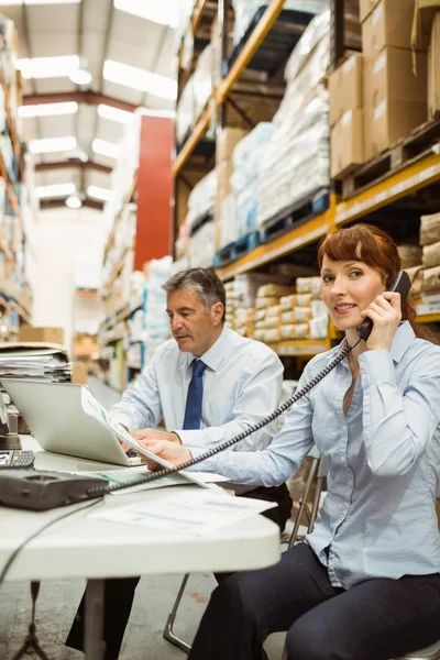 Gerente trabalhando no laptop e falando no telefone na mesa — Fotografia de Stock