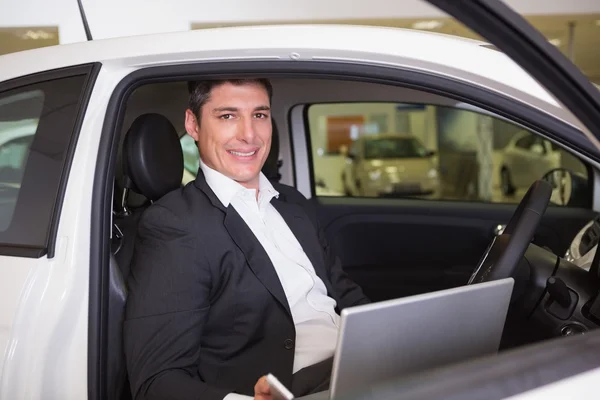 Uśmiechający się biznesmen korzysta z laptopa w swoim samochodzie — Zdjęcie stockowe