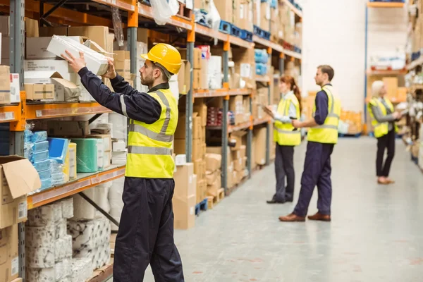 Magazijn werknemer nemen pakket in de winkelrekken — Stockfoto