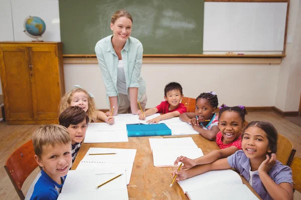 Teacher and pupils working at desk together — Stock Photo, Image