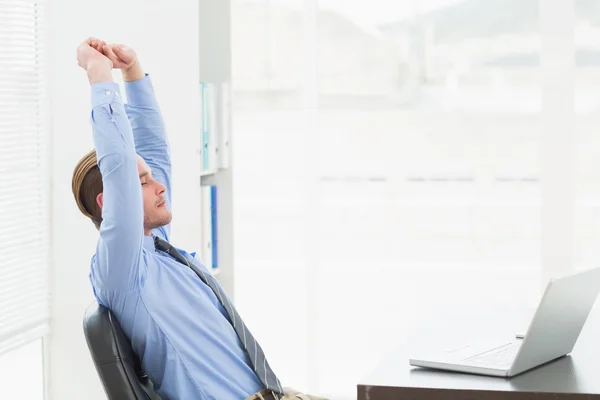 Zakenman die zich uitstrekt aan zijn bureau gericht — Stockfoto