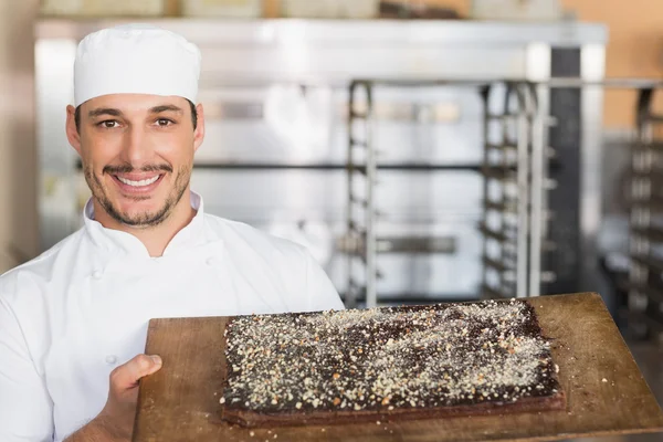 Baker showing freshly baked brownie — Stock Photo, Image