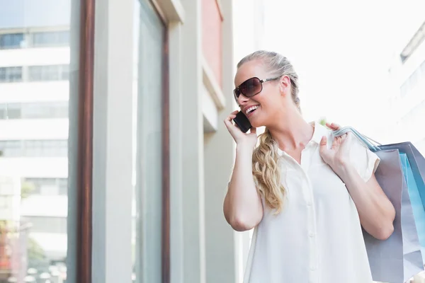 Blonde making a call holding shopping bags — Stock Photo, Image