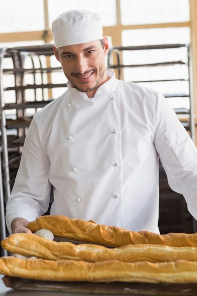 Baker looking at freshly baked baguettes — Stock Photo, Image
