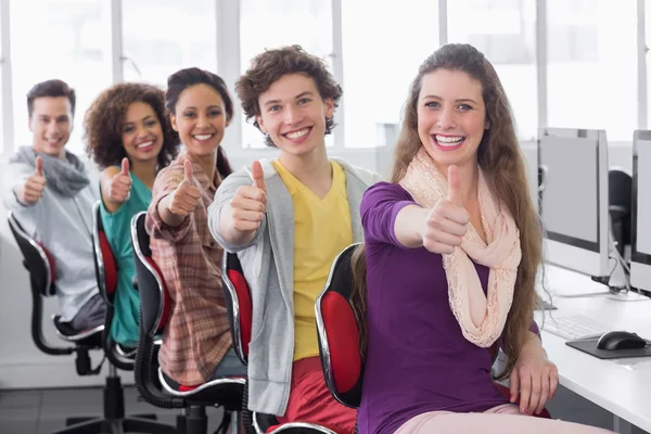 Estudantes sorrindo para a câmera e segurando os polegares para cima — Fotografia de Stock