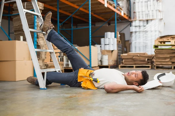 Trabalhador deitado no chão no armazém — Fotografia de Stock