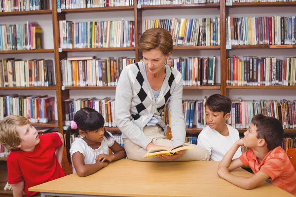 Lindos alumnos y profesor de lectura en la biblioteca —  Fotos de Stock