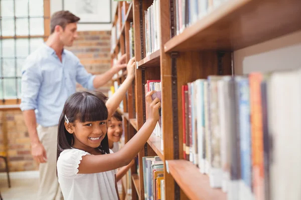 Lindos alumnos y profesores en busca de libros en la biblioteca —  Fotos de Stock