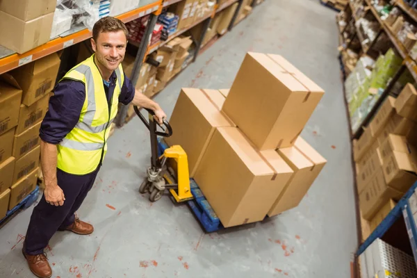 Werknemer met trolley van vakken glimlachen op camera — Stockfoto