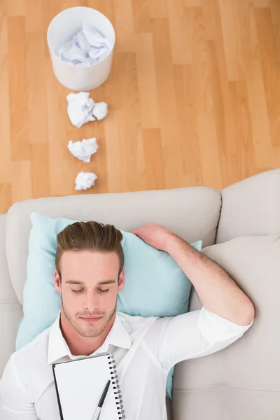 Hombre descansando en el sofá con bloque de escritor — Foto de Stock