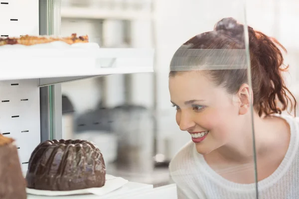 Bella bruna guardando la torta — Foto Stock