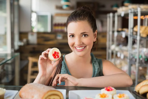 Söt brunett visar en cupcake — Stockfoto