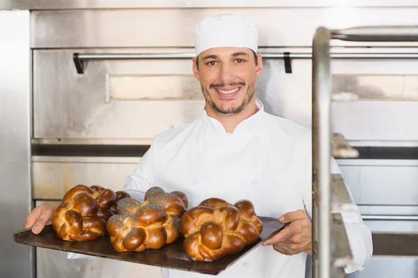 Assadeira feliz mostrando bandeja de pão fresco — Fotografia de Stock