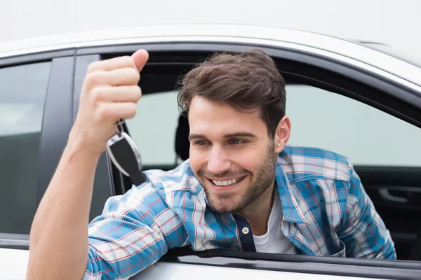 Junger Mann lächelt und hält Schlüssel in der Hand — Stockfoto