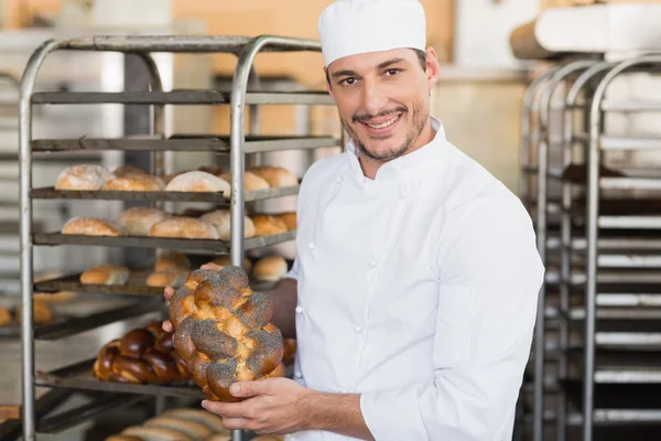 Χαμογελώντας baker κρατώντας το φρέσκο καρβέλι — Φωτογραφία Αρχείου