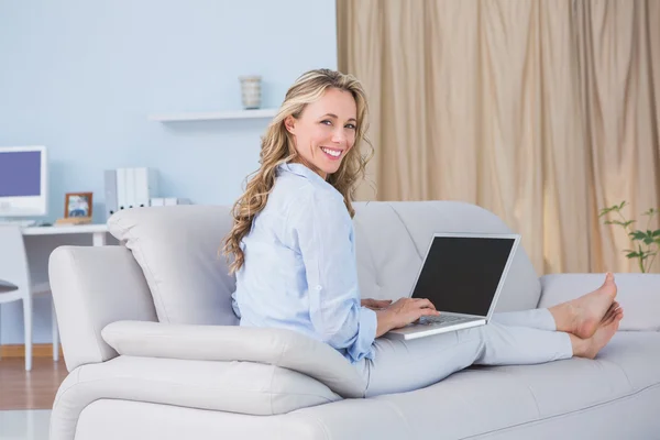Lächelnde Blondine auf Couch mit Laptop — Stockfoto