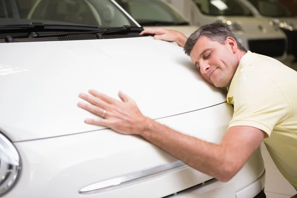 Улыбающийся мужчина обнимает белую машину — стоковое фото