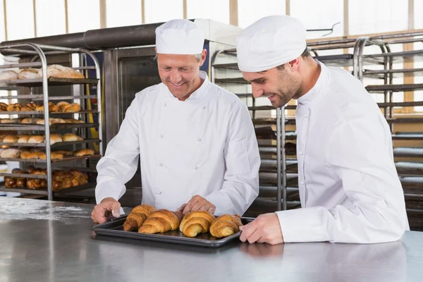 Пекари смотрят на подносы с круассанами — стоковое фото