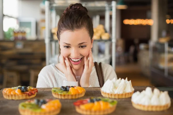 Pretty brunette looking at tarts — Stock Photo, Image