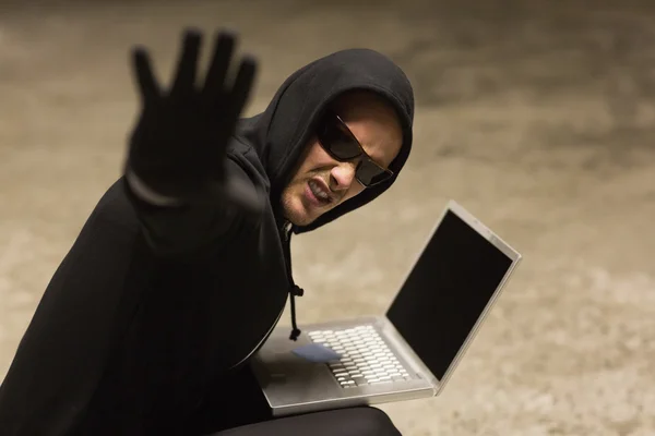 Frowning hacker in sunglasses gesturing — Stock Photo, Image