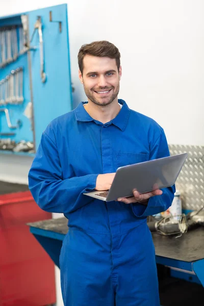 Mechanic smiling using laptop — Stock Photo, Image