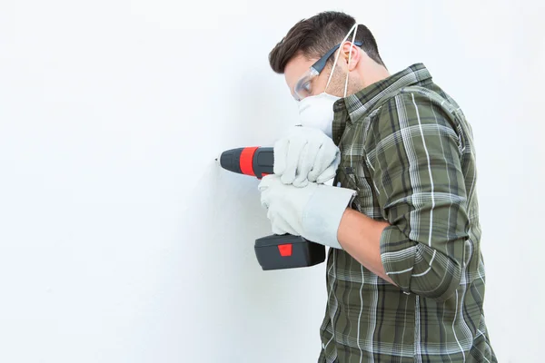 Carpintero con máquina perforadora en pared blanca —  Fotos de Stock