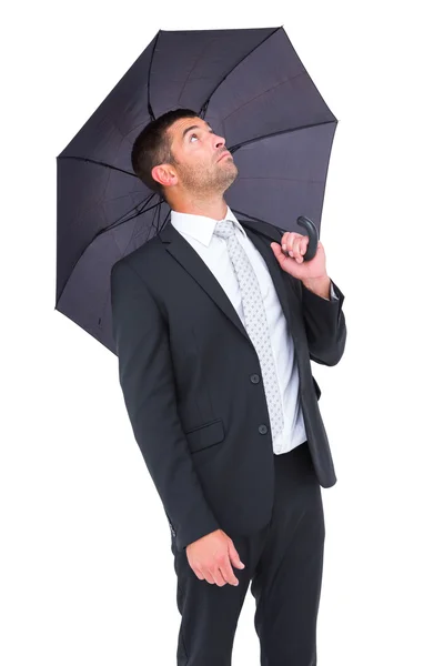 Geschäftsmann versteckt sich unter schwarzem Regenschirm — Stockfoto