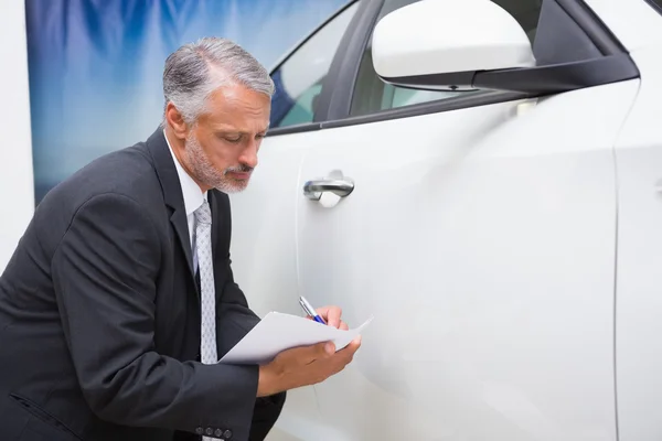 Zakenman kijken naar auto tijdens het schrijven op Klembord — Stockfoto