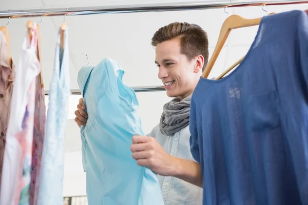 Smiling student holding a blue shirt — Stock Photo, Image