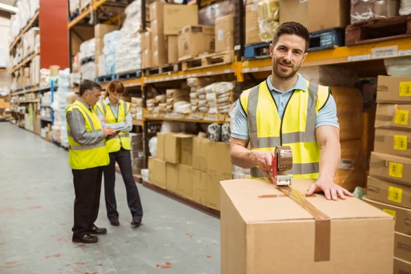 Trabalhadores sorrindo armazém preparando uma remessa — Fotografia de Stock